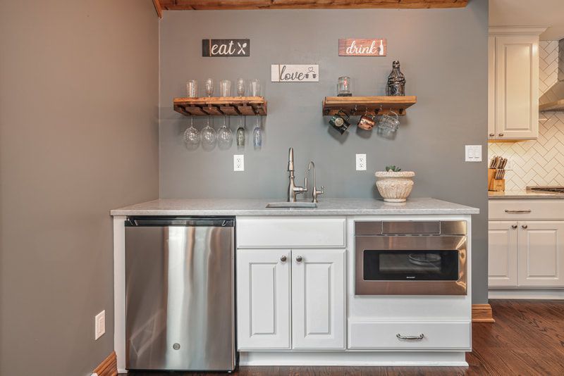 A kitchen with white cabinets , stainless steel appliances , a sink and a microwave.