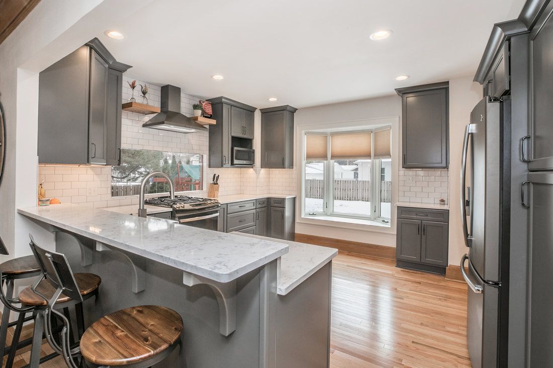 A kitchen with gray cabinets , granite counter tops , stainless steel appliances and a large island.
