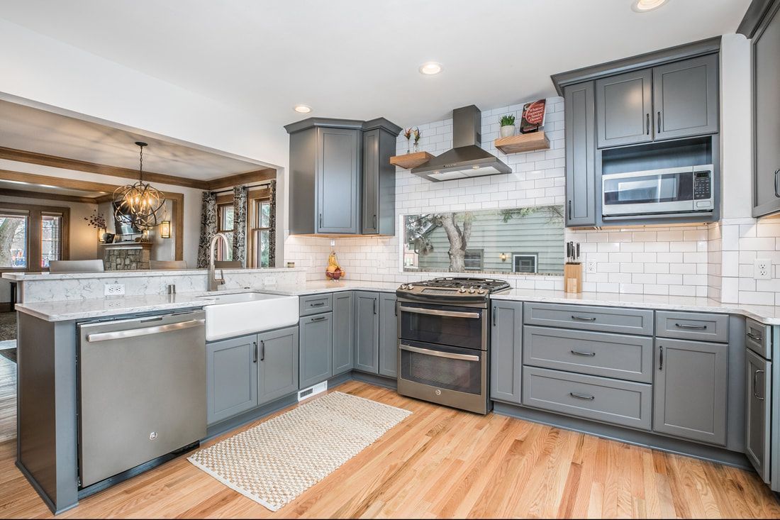 A kitchen with gray cabinets , stainless steel appliances , a sink , and a stove.