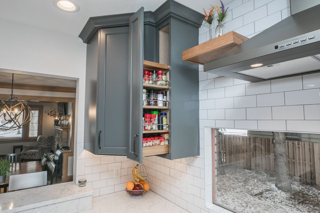 A kitchen with gray cabinets and a pull out pantry.