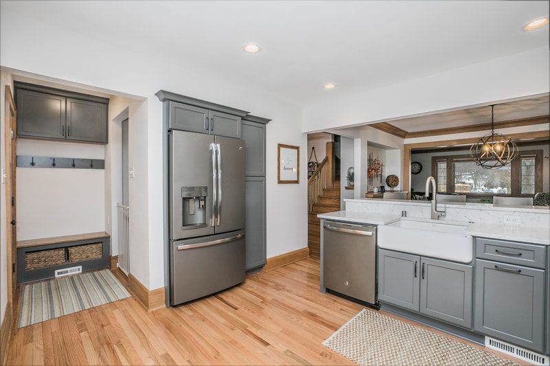 A kitchen with gray cabinets , stainless steel appliances , a refrigerator and a sink.