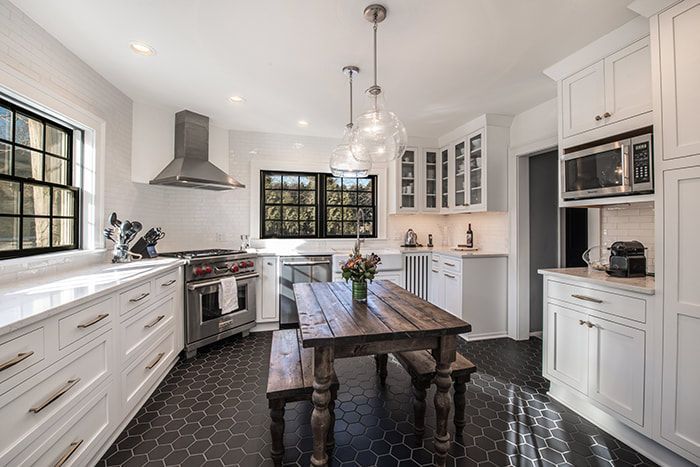 A kitchen with white cabinets , a wooden table and benches.