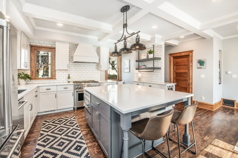 A kitchen with white cabinets , stainless steel appliances , and a large island.