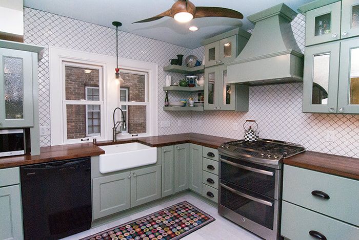 A kitchen with green cabinets and a ceiling fan