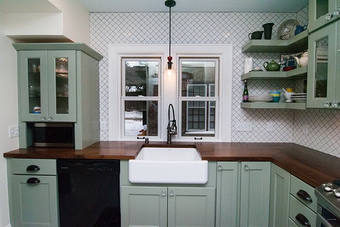 A kitchen with green cabinets and a white sink.