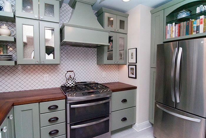 A kitchen with stainless steel appliances and green cabinets
