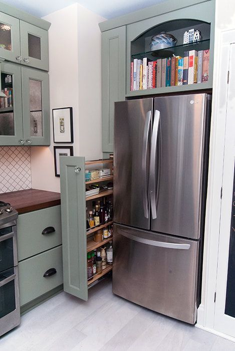 A kitchen with a stainless steel refrigerator and a pull out pantry.