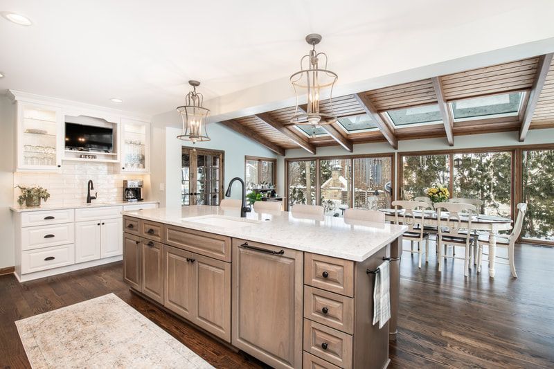 A kitchen with a large island in the middle and a dining room in the background.