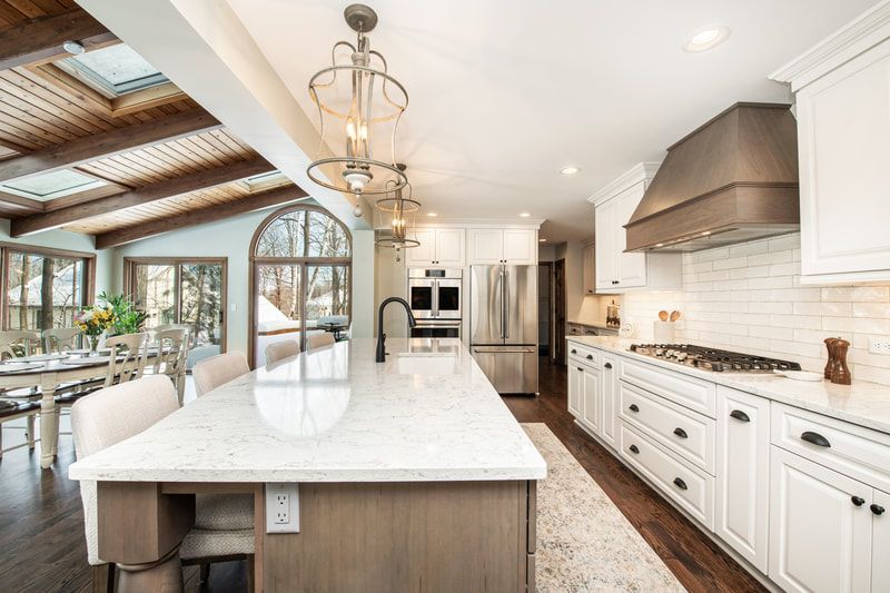 A kitchen with white cabinets , granite counter tops , stainless steel appliances and a large island.