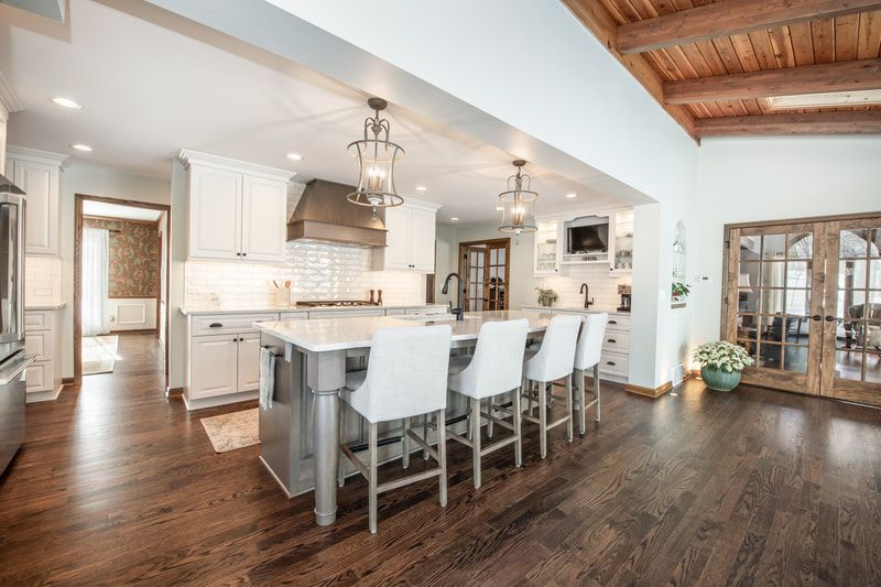 A kitchen with a large island and white chairs.