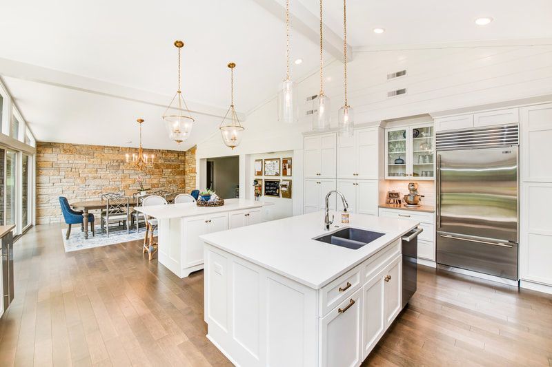 A kitchen with white cabinets and stainless steel appliances and a large island in the middle.