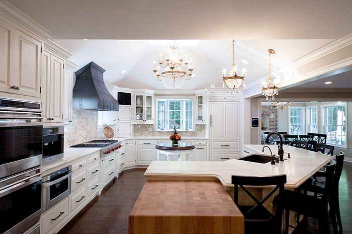A kitchen with white cabinets and stainless steel appliances and a large island.