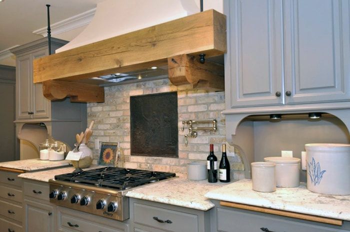 A kitchen with a stove top oven and a wooden hood.