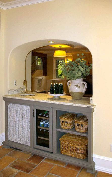 A kitchen with a wine cooler and wicker baskets