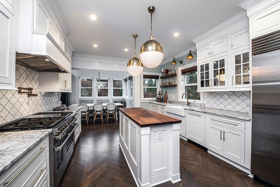A kitchen with white cabinets and stainless steel appliances and a large island in the middle.