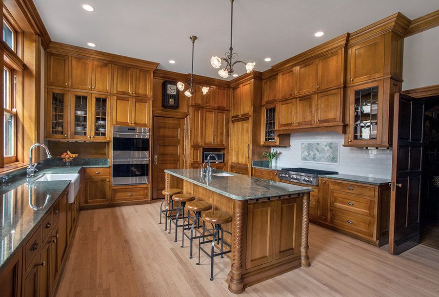 A large kitchen with wooden cabinets , granite counter tops , stainless steel appliances and a large island.