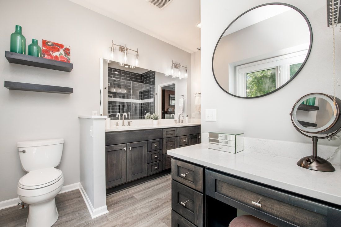 A bathroom with a toilet , sink , mirror and vanity.