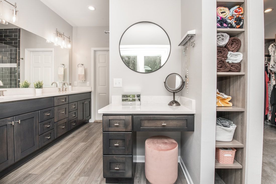 A bathroom with a vanity , mirror and ottoman.