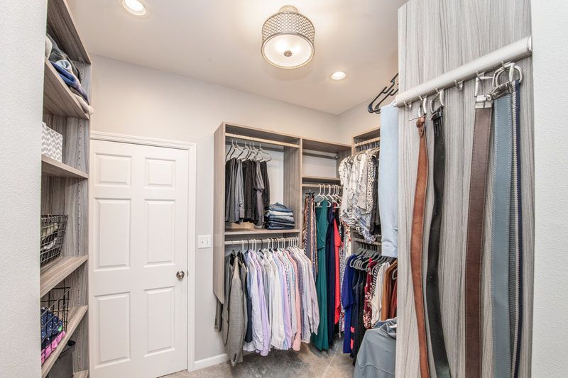 A walk in closet filled with lots of clothes and belts.