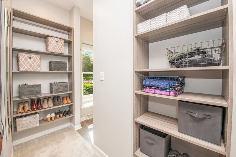 A walk in closet with shelves filled with clothes and shoes.