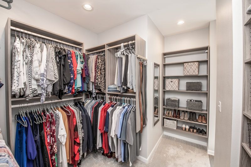 A walk in closet filled with lots of clothes and shoes.