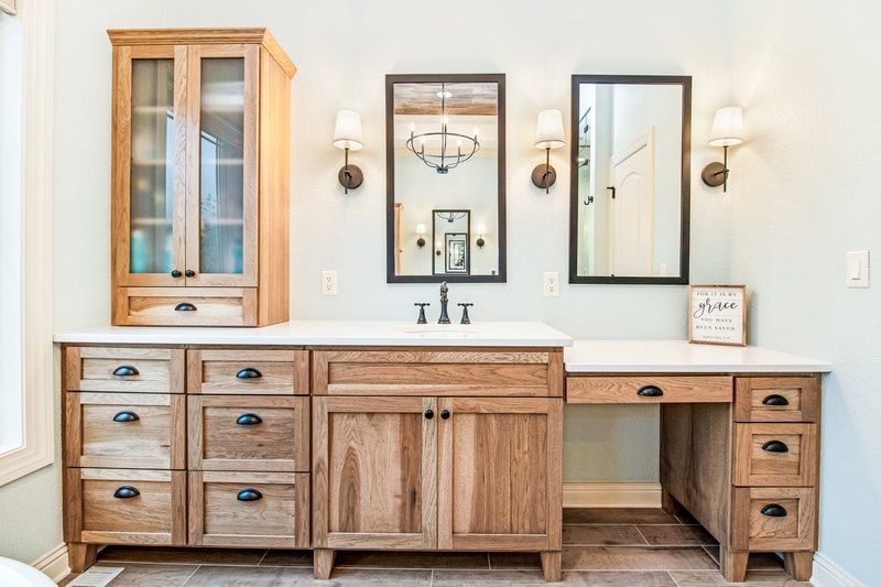 A bathroom with a sink , mirrors , cabinets and drawers.