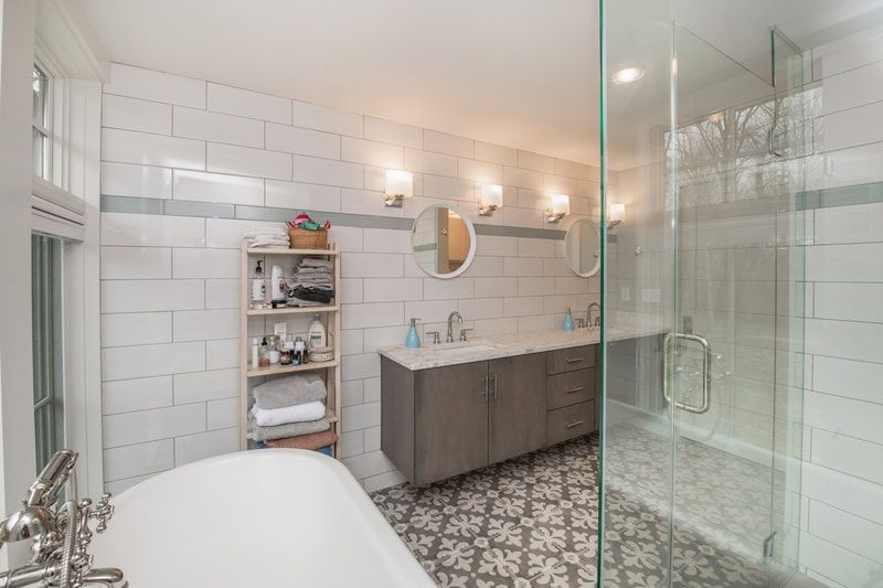 A bathroom with a tub , sink , mirrors and a walk in shower.