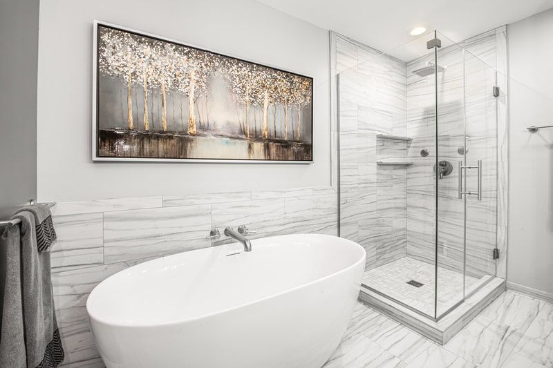 A bathroom with a bathtub , shower , and painting on the wall.