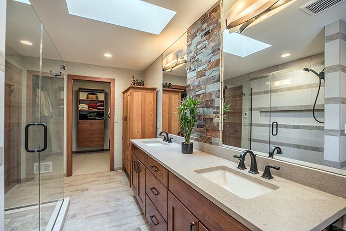 A bathroom with two sinks , a shower and a skylight.
