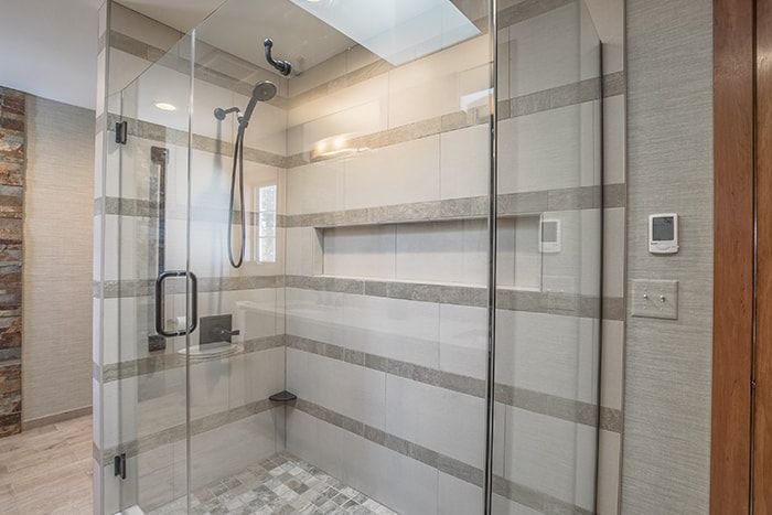 A bathroom with a walk in shower with a glass door.
