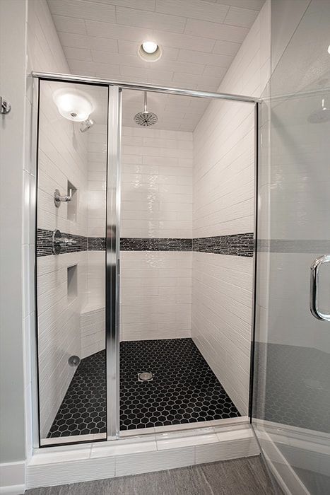 A bathroom with a walk in shower with a glass door.