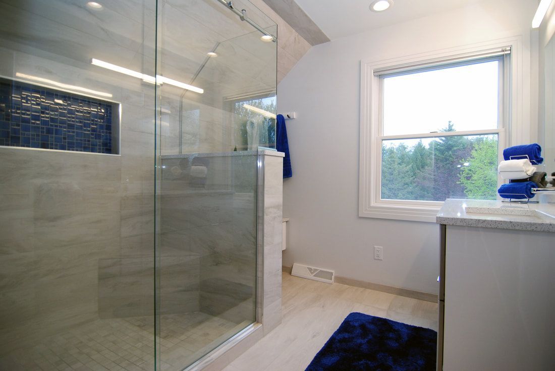 A bathroom with a walk in shower , sink , and window.