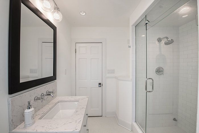 A bathroom with a sink , mirror and shower.