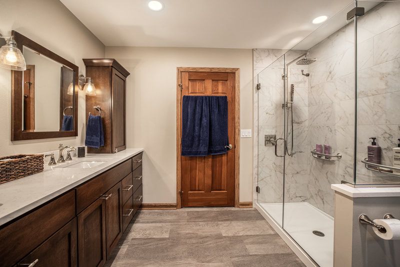 A bathroom with two sinks , a mirror and a walk in shower.