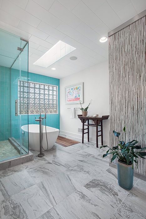 A bathroom with a tub , shower , and skylight.