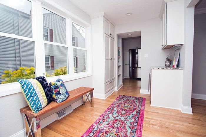 A hallway with a bench and a rug in a house.