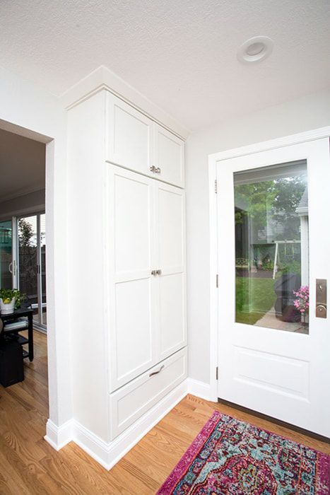A white cabinet in a hallway next to a door.