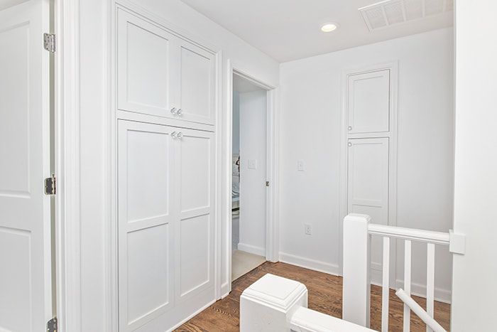 A hallway with white cabinets and a staircase in a house.