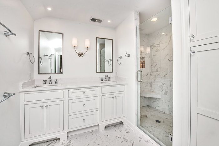 A bathroom with two sinks and a walk in shower.