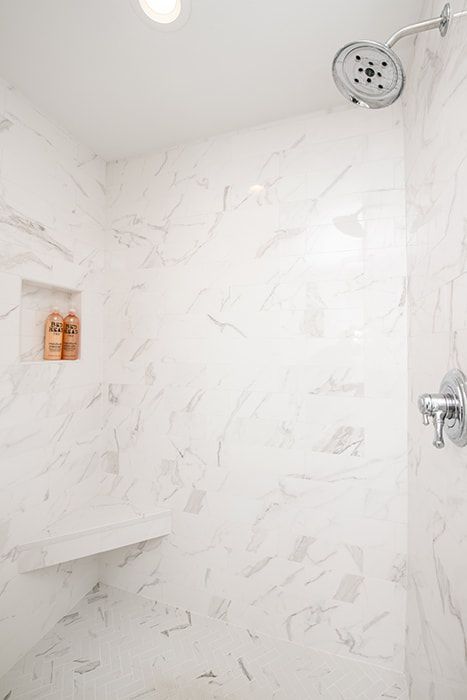 A shower with a bench and a shower head in a bathroom.