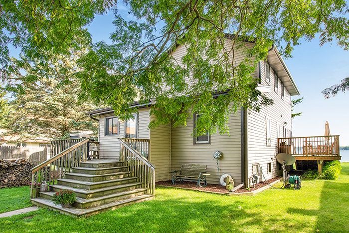 The back of a house with a deck and stairs leading up to it.
