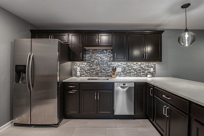 A kitchen with stainless steel appliances and dark cabinets.