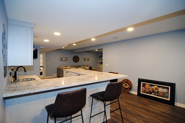 A kitchen with a bar and stools in a basement.