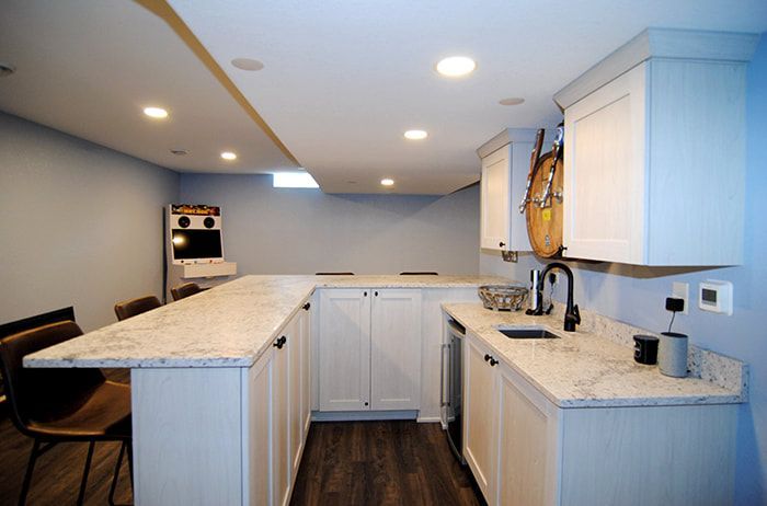 A kitchen with white cabinets and marble counter tops