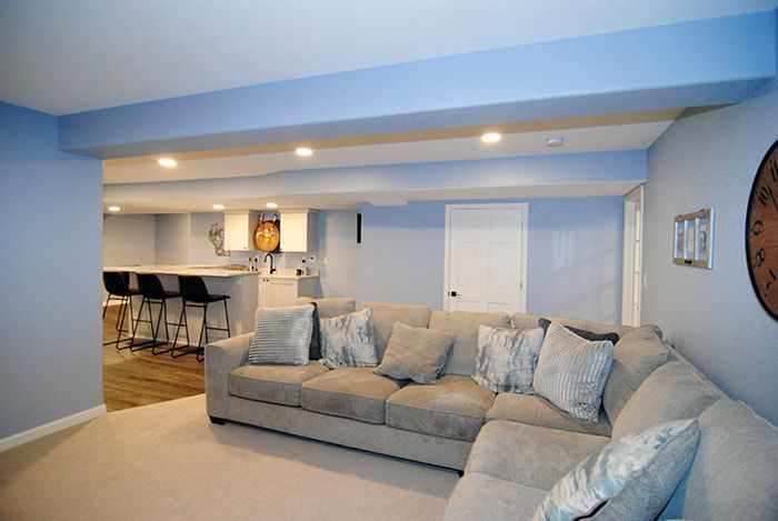 A living room with a couch and a clock on the wall.