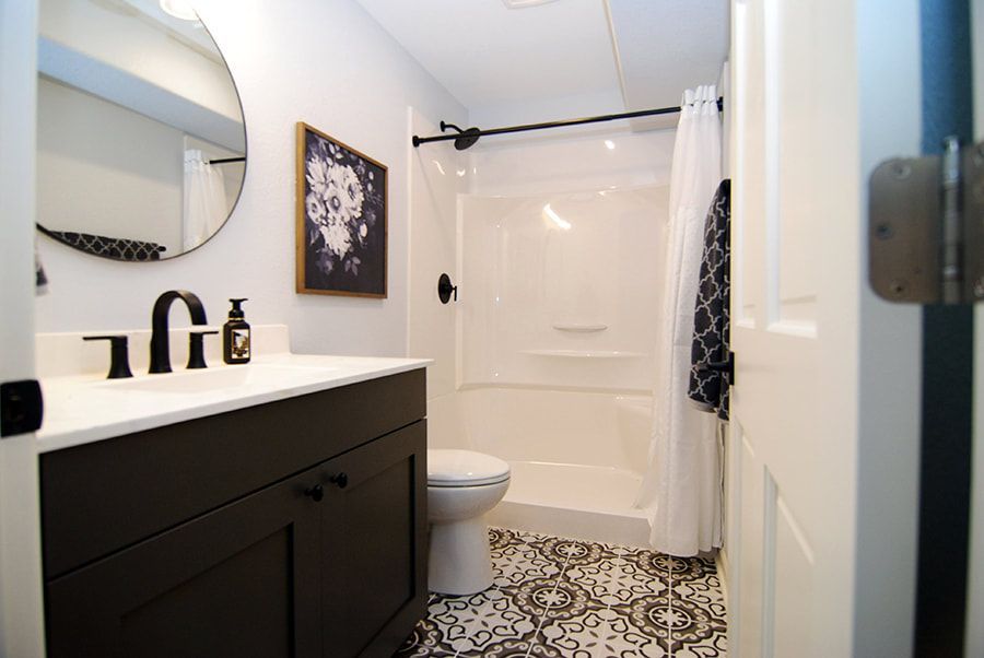 A bathroom with a toilet , sink , mirror and shower.