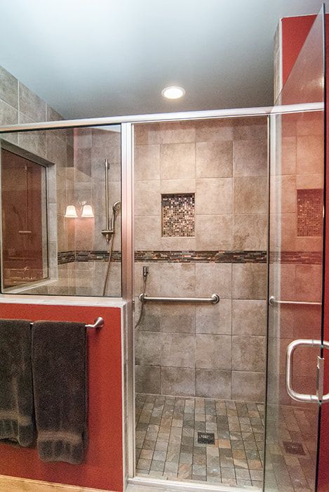 A bathroom with a walk in shower with a glass door