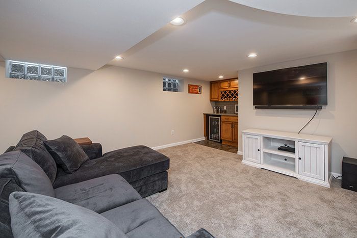 A living room in a basement with a couch and a flat screen tv.