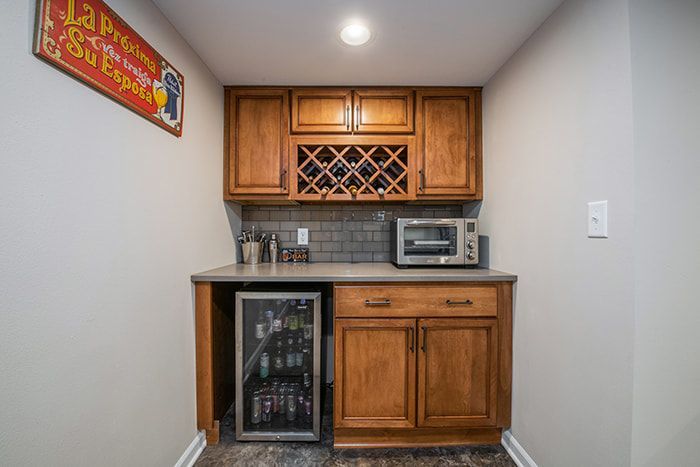 A kitchen with wooden cabinets , a refrigerator , a microwave , and a wine rack.