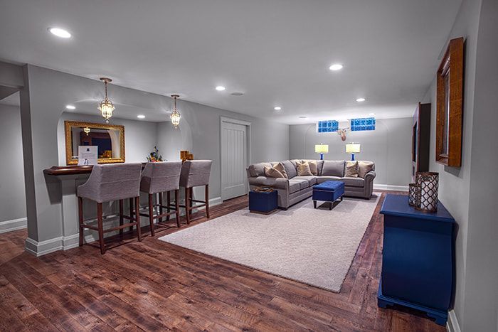 A living room in a basement with hardwood floors and a couch.